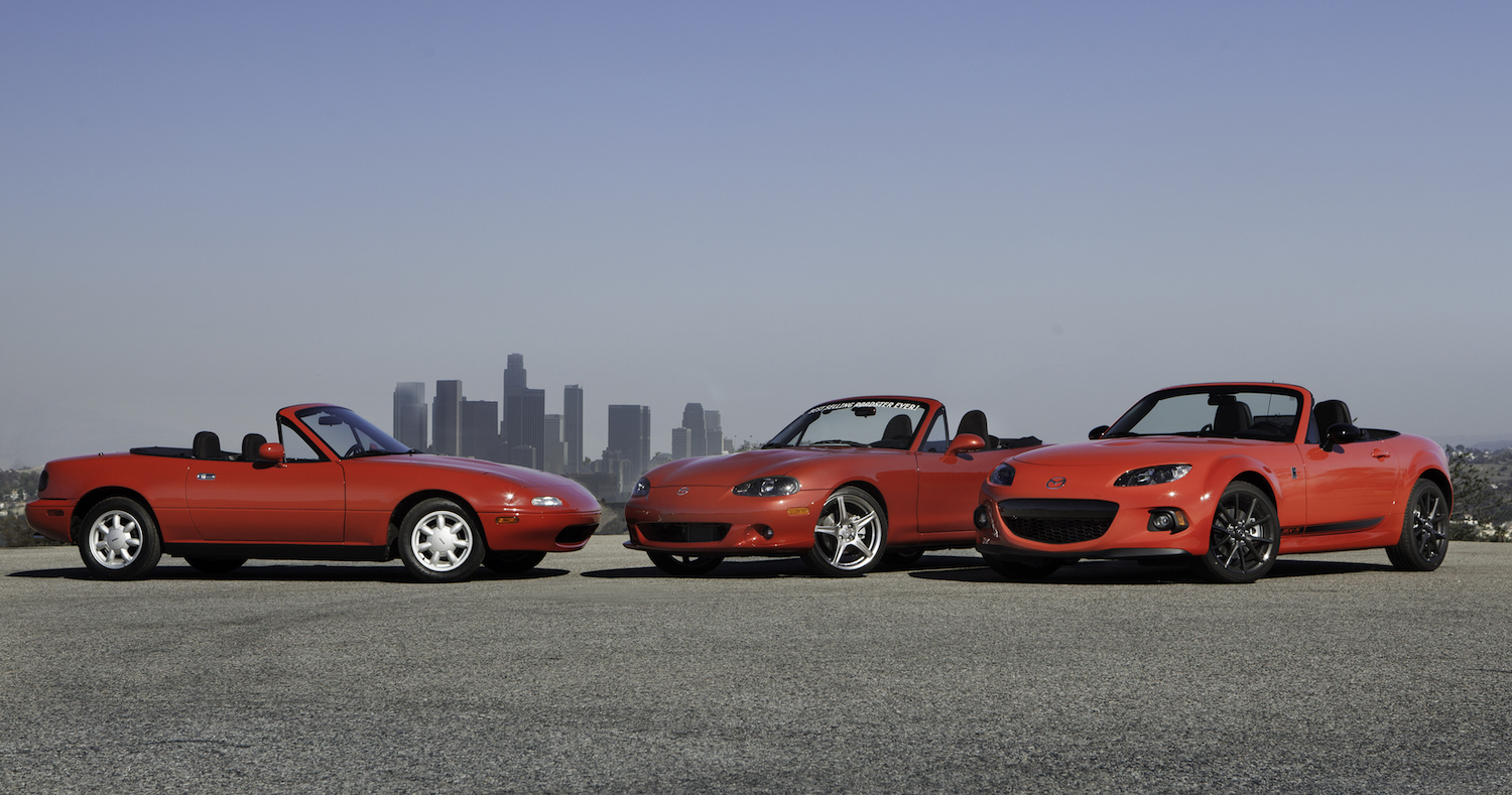 Three reliable used Mazda Miata convertibles, an NA, NB, and ND MX-5, all finished in red and parked in front of the L.A. skyline for a publicity photo.
