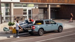 People loading a sofa onto a new 2023 Ford Maverick pickup truck, highlighting how much a fully loaded one costs