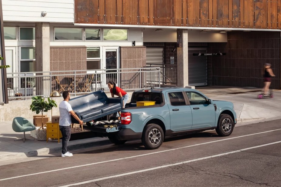 People loading a sofa onto a new 2023 Ford Maverick pickup truck, highlighting how much a fully loaded one costs