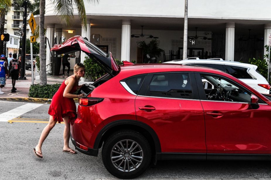 Person loading luggage in a new SUV model that is red. 