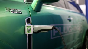 Closeup of a plug-in hybrid's charger set into its green fender, PHEV badge visible in the foreground.