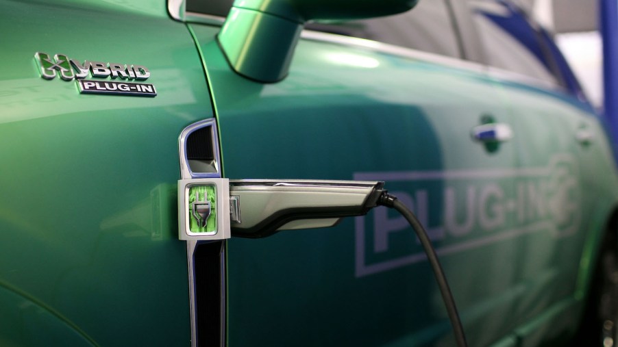 Closeup of a plug-in hybrid's charger set into its green fender, PHEV badge visible in the foreground.