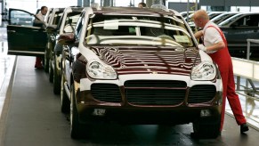 A line of mid-2000s Porsche Cayenne SUVs being assembled in a factory in Germany.