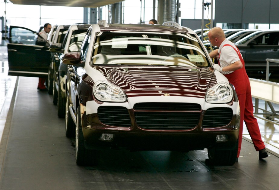 A line of mid-2000s Porsche Cayenne SUVs being assembled in a factory in Germany.