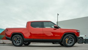 Red Rivian electric truck parked outside the manufacturer's factory.