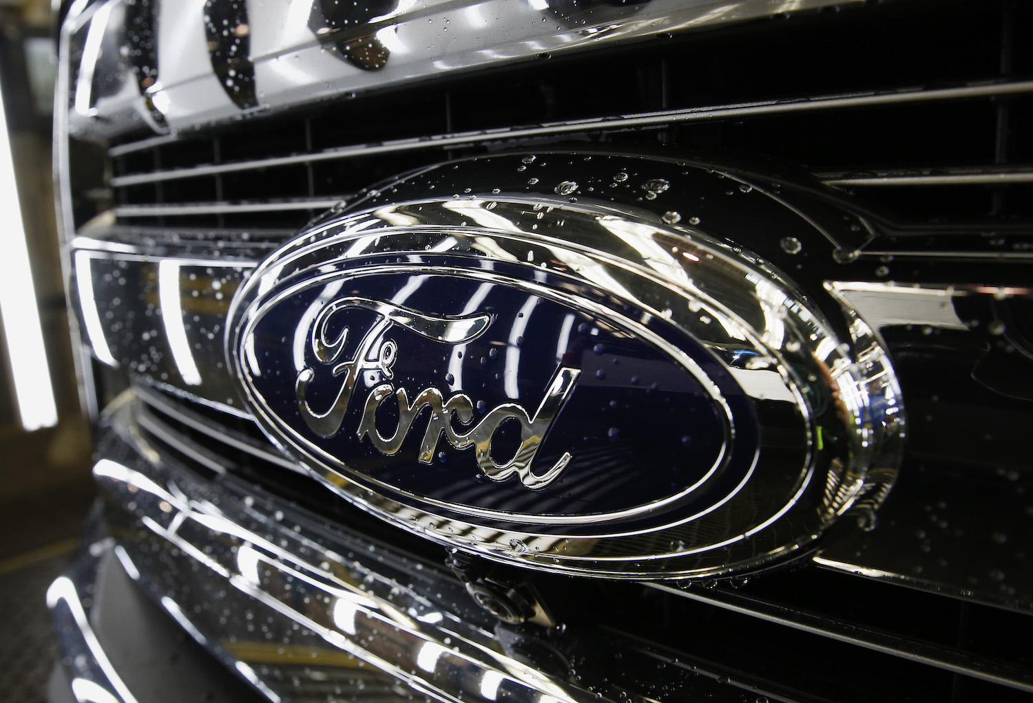 Close up of Ford Blue Oval logo on chrome grille of reliable used American F-150 truck.
