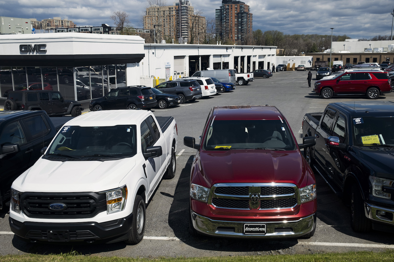 A row of reliable used pickup trucks including a Dodge Ram 1500 and Ford F-150, parked in a dealership lot.