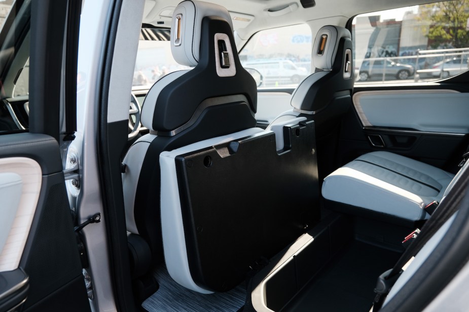 The white leather interior of a Rivian electric truck with USB-C power outlets built into its seat headrests.