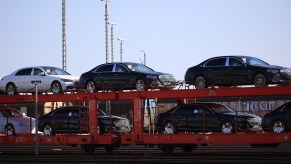 A person carrying a slew of cars where they are shipping a car.