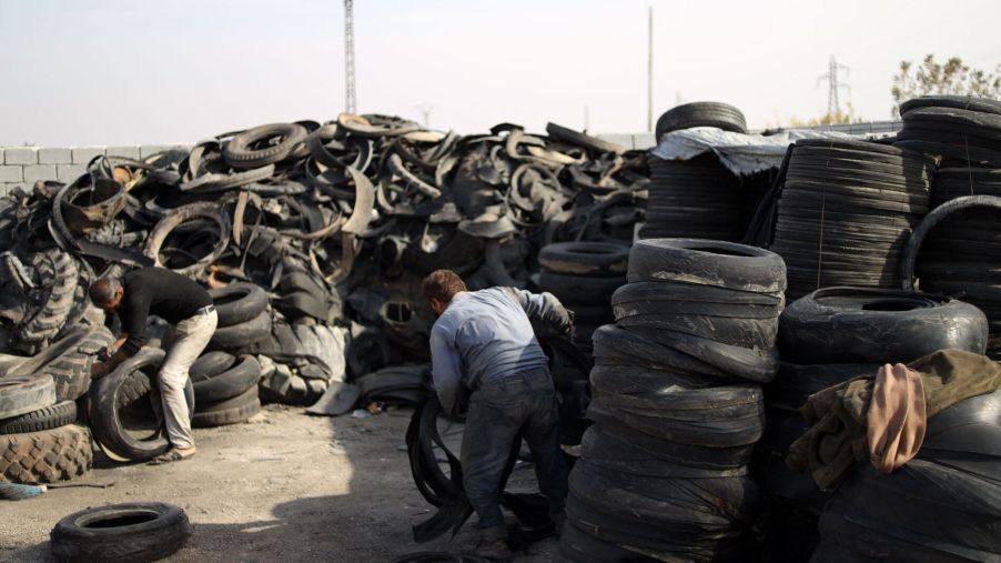A man works in a tire recycling center to recycle tires after they've been driven on for years.