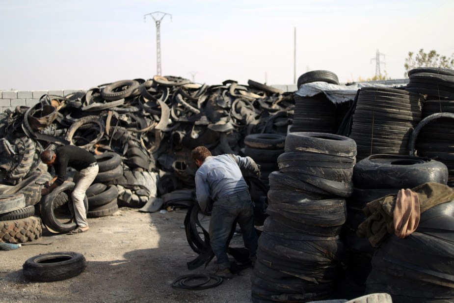 A man works in a tire recycling center to recycle tires after they've been driven on for years.