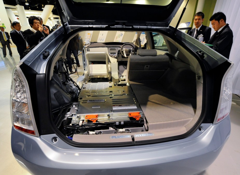 Early PHEV Toyota Prius's trunk with its Li-ion battery pack exposed, parked at an auto show.