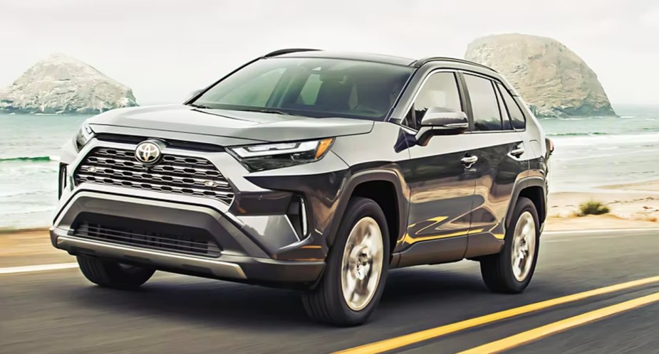A gray 2023 Toyota RAV4 small SUV is driving on the road. 