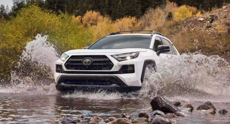 A white 2022 Toyota RAV4 small SUV is driving off-road.