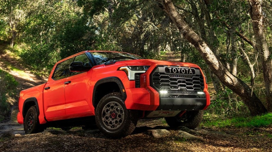 Orange Toyota Tundra TRD Pro full size off road pickup going up a hill in the woods