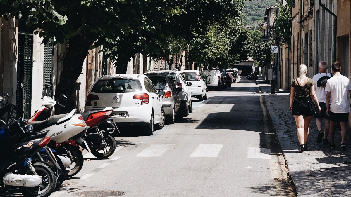 Vehicles parked on a street, highlighting broken moped parking trick to save spot when not home