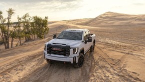 White 2024 GMC Sierra HD on sand, possibly in a desert setting