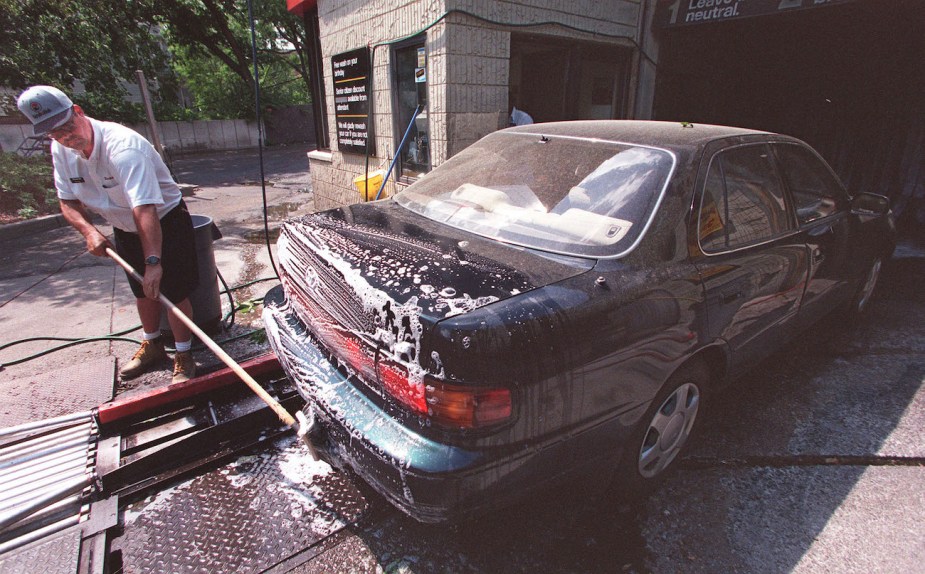 A car wash attendant washes pollen off a car.