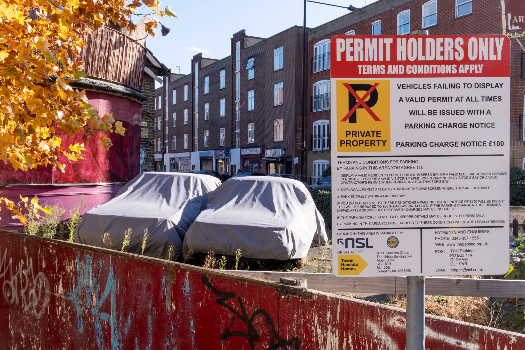 Two covered cars parked on private and personal property with a permit sign in London, England