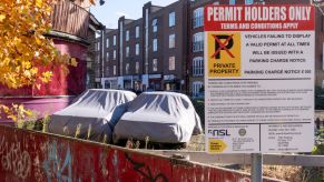 Two covered cars parked on private and personal property with a permit sign in London, England