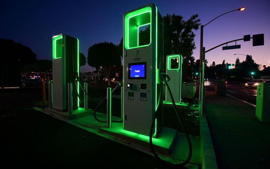 A bank of EV chargers illuminated, the sunset visible behind them.