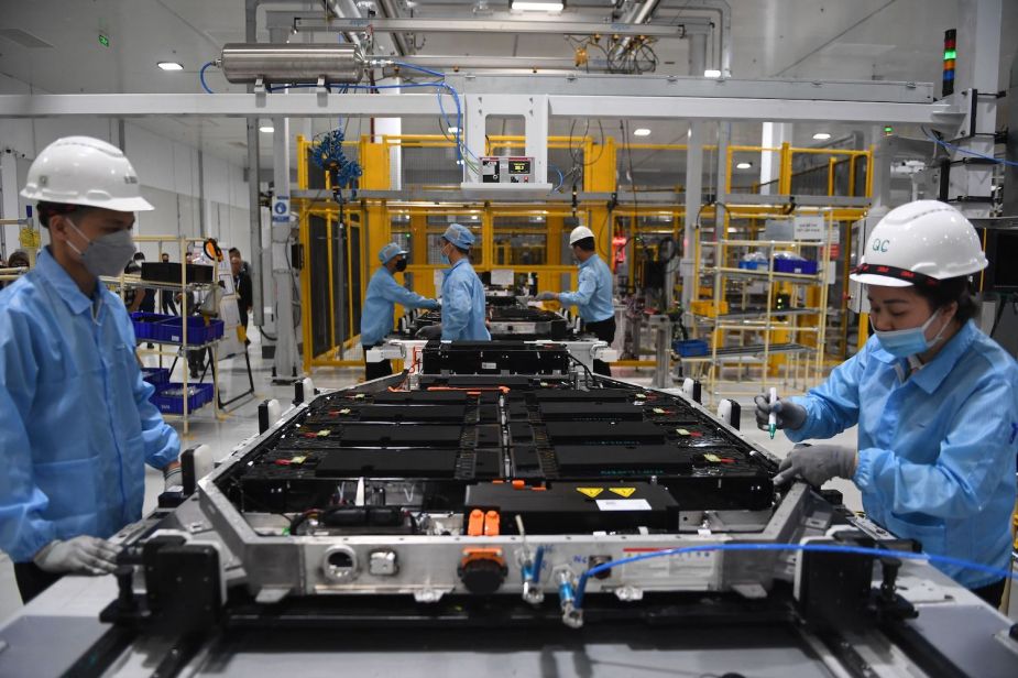 Two factory workers assembling the extended range upgraded battery pack going into an electric vehicle (EV).