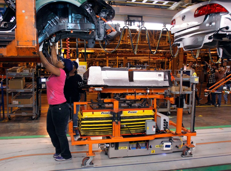 A Detroit assembly line worker preparing a Chevrolet Volt plug-in hybrid PHEV for its large size Li-ion battery pack, visible in the foreground. 