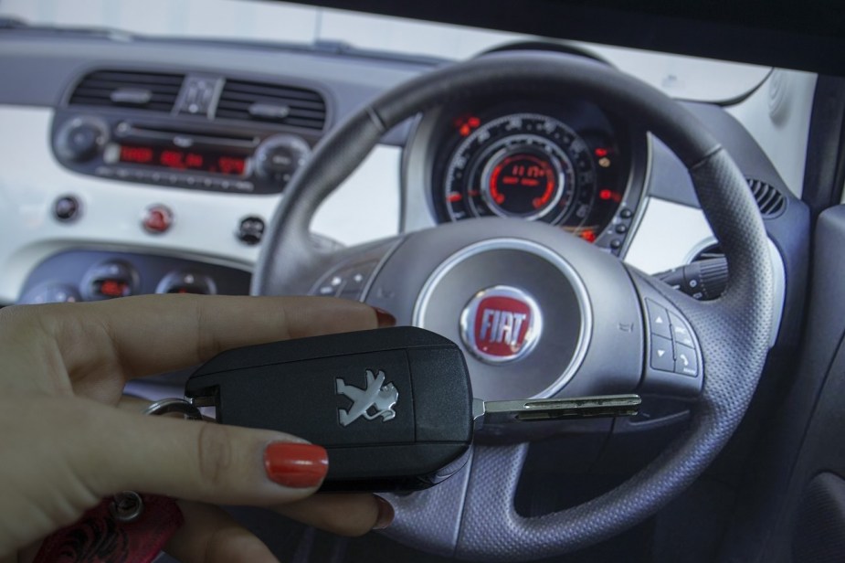 A woman holds a Peugeot car key.