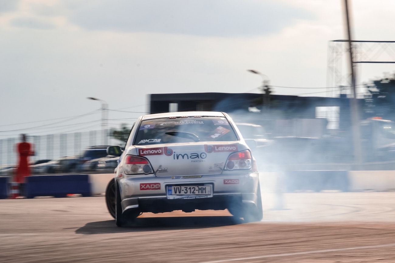 The rear view of a Subaru WRX in the middle of a drift.
