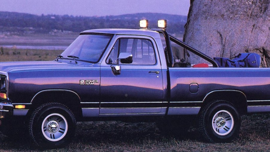 A 1990 Dodge Ram D150 pickup truck with two-tone paint, parked in front of a construction site.