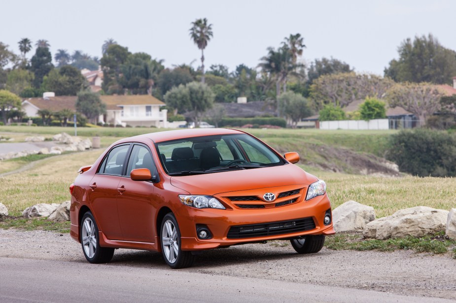 Orange special edition 2013 Toyota Corolla sedan parked next to a road, houses visible in the background.