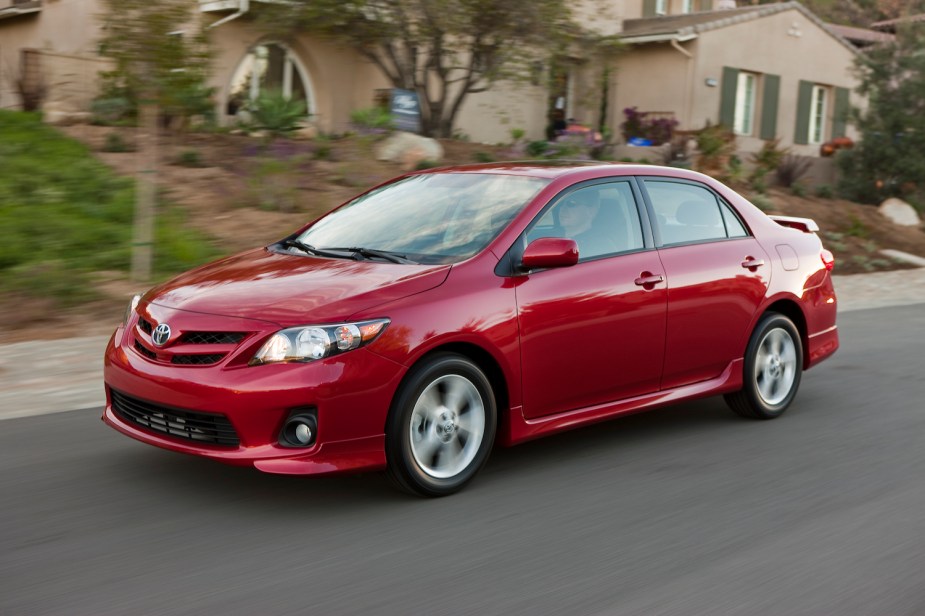 This is a red 2013 Toyota Corolla sedan driving down a residential street.