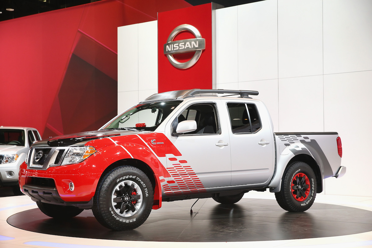 A white and red 2014 Nissan Frontier, reliable small used pickup trucks.