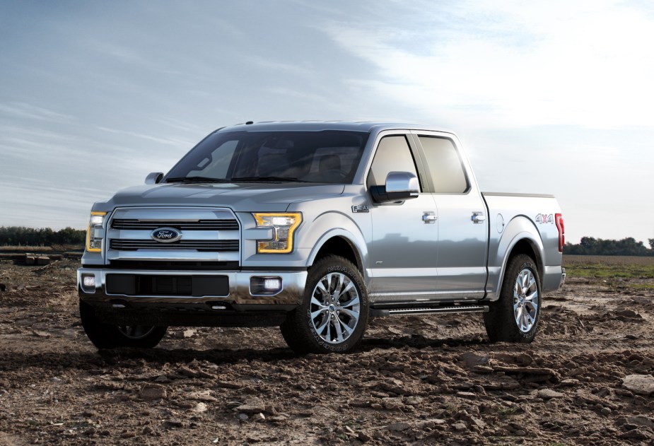Silver, aluminum bodied 2015 Ford F-150 pickup truck parked on a dirt plain.