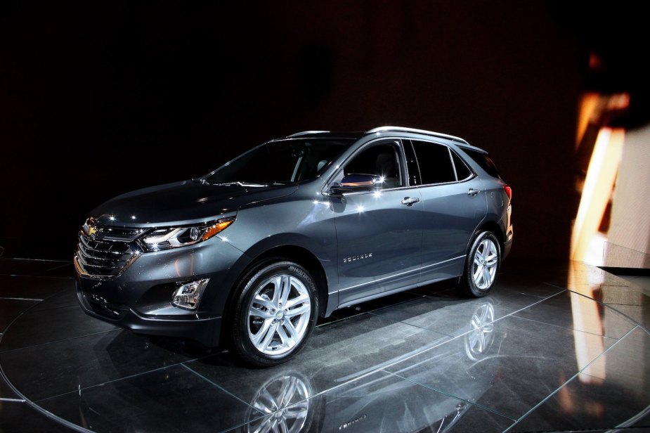 A gray 2017 Chevrolet Equinox parked on the stage at the Chicago Auto Show, a black background behind it.