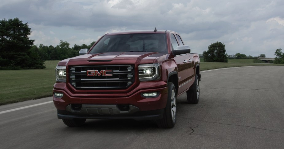 Red 2017 GMC Sierra driving on the highway, clouds visible in the background.