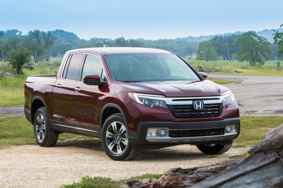 A maroon red 2017 Honda Ridgeline midsize pickup truck parked off-road for an advertising photo showing off its second-generation redesign.