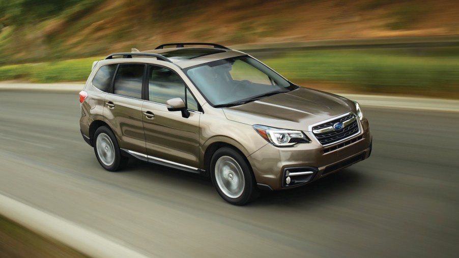 Promo photo of a beige Subaru Forester driving along a road, the woods behind it a green blur.