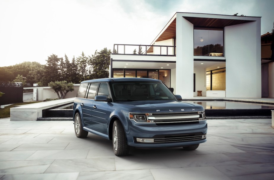 A 2019 Ford Flex midsize crossover SUV parked in a driveway, a modern mansion visible in the background.