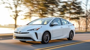 A white 2019 Toyota Prius driving, the Toyota Prius is a used car with a high price