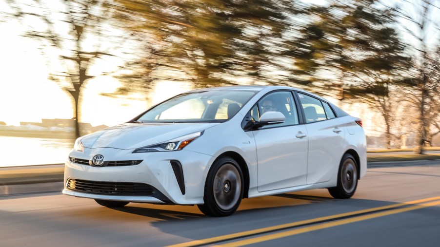 A white 2019 Toyota Prius driving, the Toyota Prius is a used car with a high price