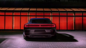 A Dodge Charger Daytona SRT Banshee EV concept car parked in front of a red, glowing window.