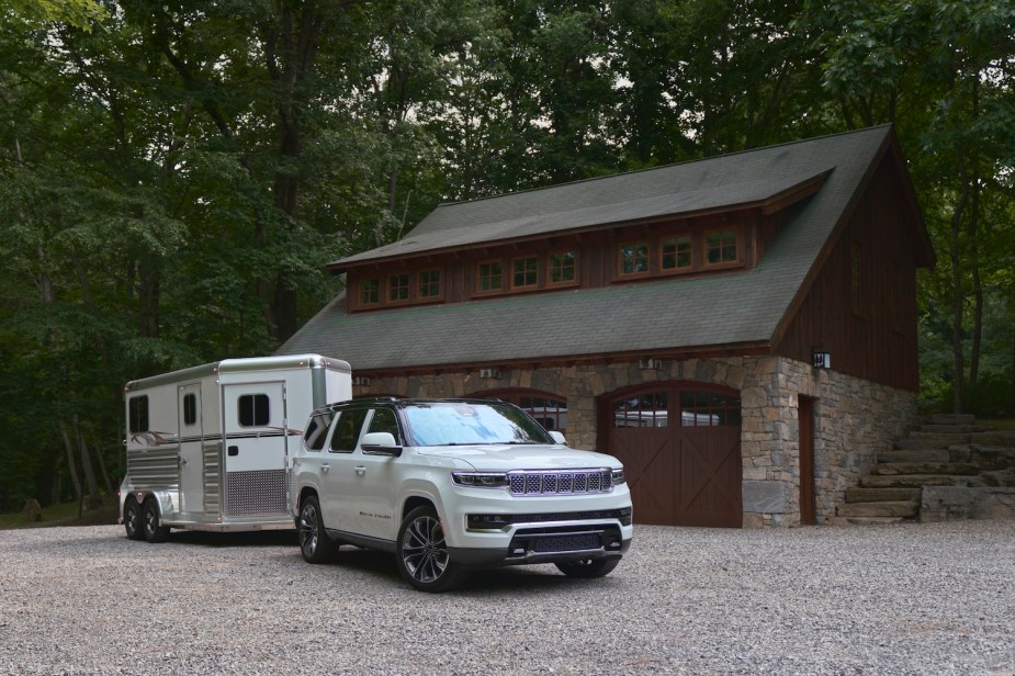 2022 Grand Wagoneer in white towin g a horse trailer by a farm.