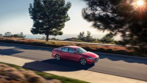 A red 2022 Hyundai Sonata driving, the Sonata is among the best gas mileage midsize cars of 2022