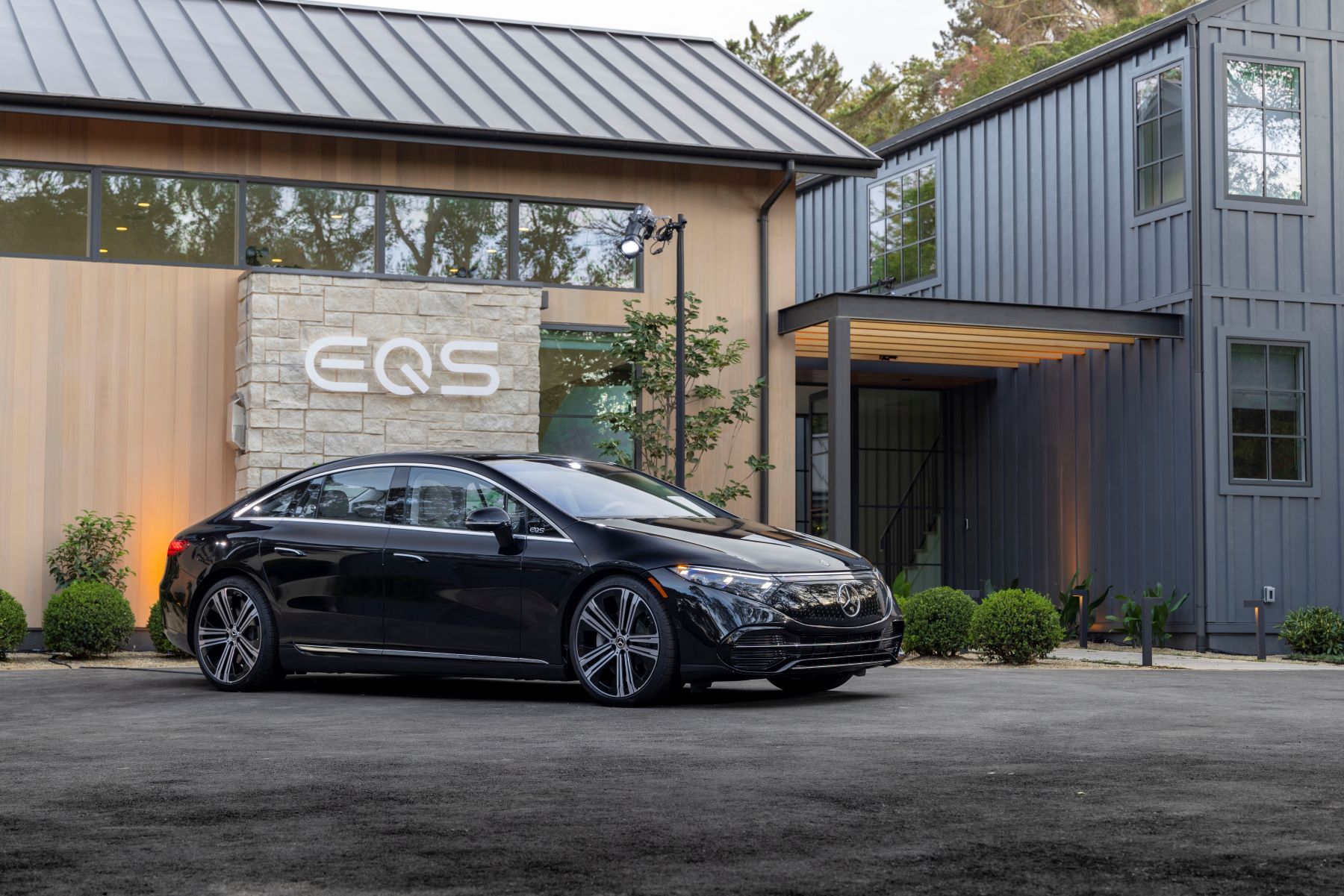 A black 2022 Mercedes-Benz EQS all electric (EV) luxury sedan model parked under its lineup branding logo