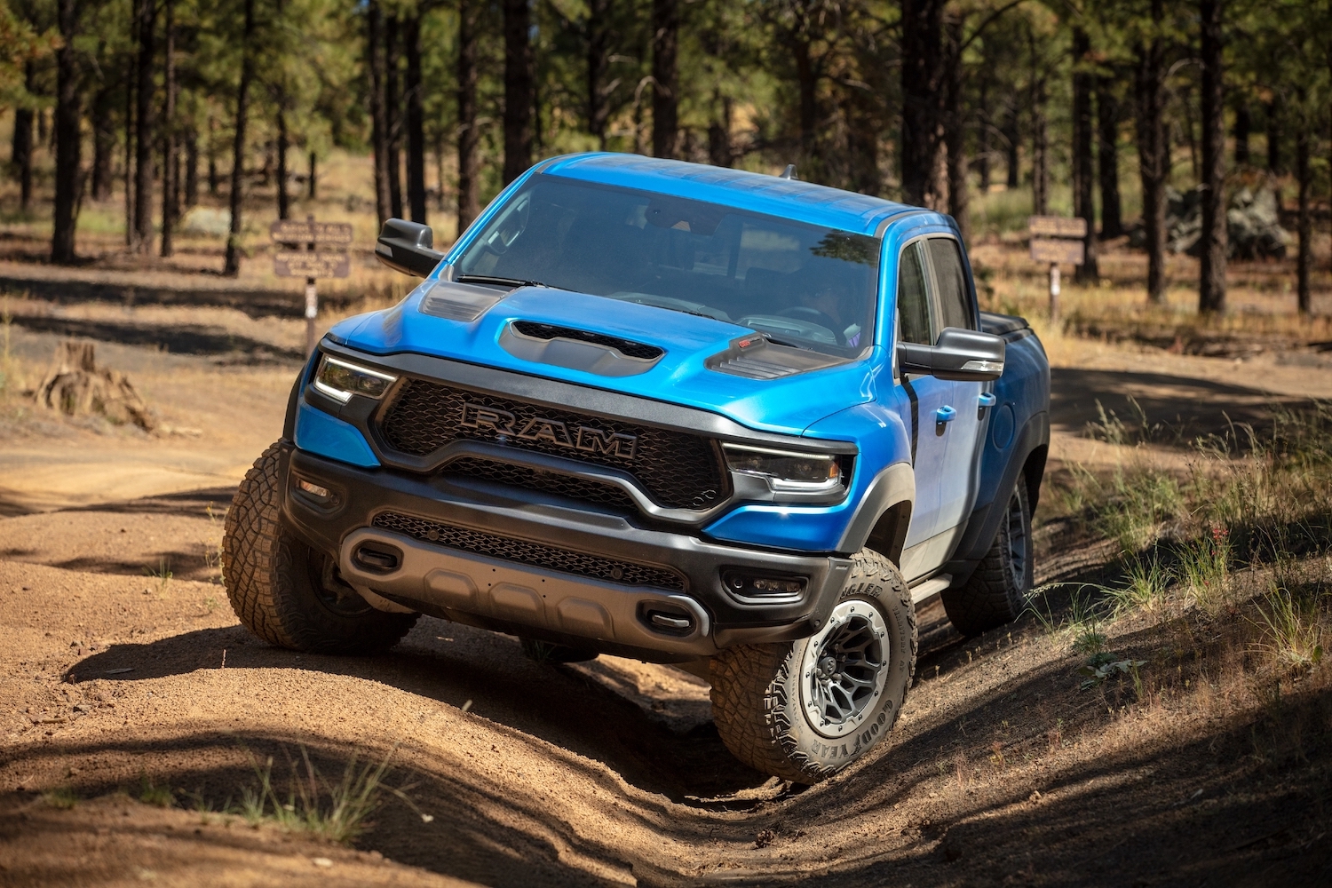 Promo photo of the supercharged Ram 1500 TRX super truck parked on a 4x4 trail, a row of trees in the background.