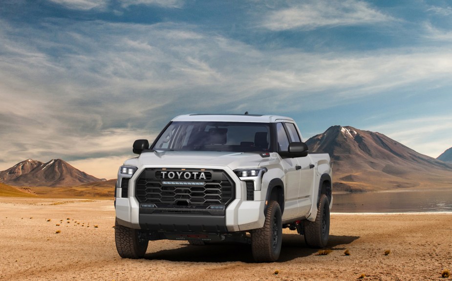 Promo photo of a white hybrid Toyota Tundra pickup truck with i-FORCE MAX turbocharged engine, parked in the desert.