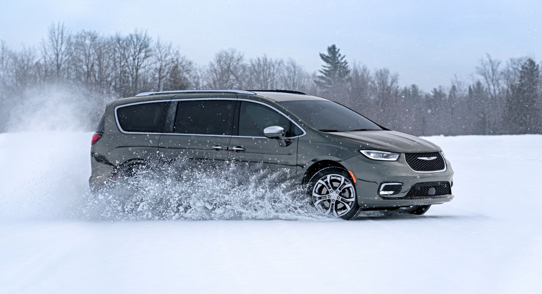 A gray 2023 Chrysler Pacifica with available all-wheel drive (AWD) driving through a snowy field