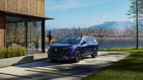 A blue 2023 Honda Consumer Reports-V parked in front of a building.