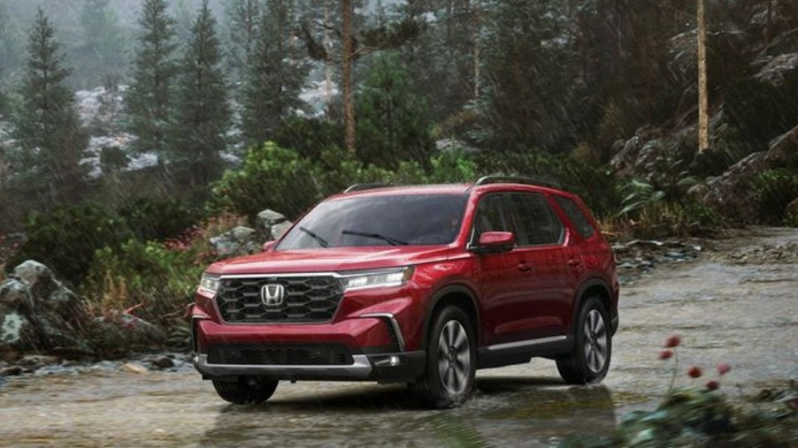 Red 2023 Honda Pilot Driving on a Wilderness Trail in the Rain